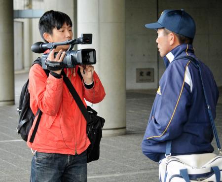 　試合後、岡田監督にインタビューする蔦哲一朗さん（左）