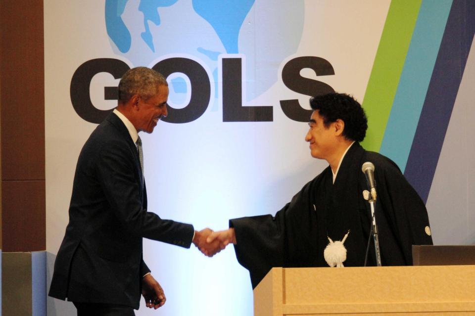 　ガッチリと握手を交わすオバマ氏（左）と半田会長