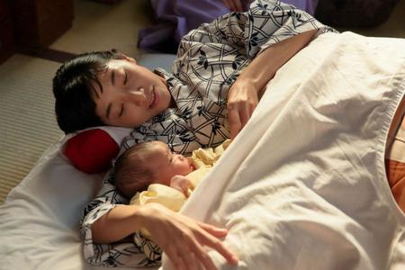 なんとか無事に出産を終え、香田家の居間で生まれたばかりの娘「幸」と添い寝する福子（安藤サクラ）