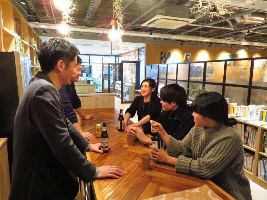 談笑する井上マネージャー（左奥）ら。ワークスペースと少し離れ、ひと息つけるバーカウンターでお酒やコーヒーを飲みながら交流を深めることが目的