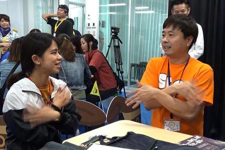 　沖縄国際映画祭の「異言語脱出ゲーム」で参加者に手話で話しかける次長課長・河本　写真提供：ＭＢＳ