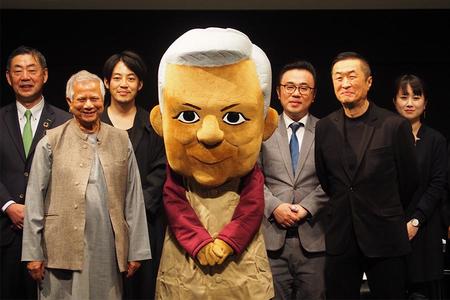 　講演をおこなったムハマド・ユヌス博士（中央左）とキャラクター・ユヌスくん（２２日・大阪市内）