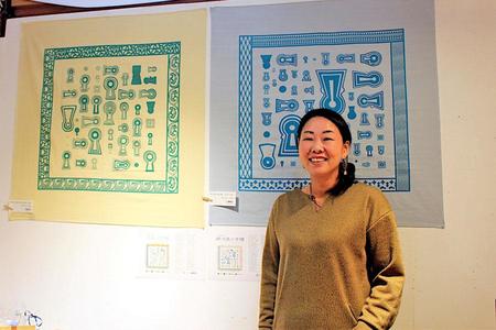 歴史意匠デザインの魅力を語るデザイナーの金田あおいさん。後ろは、奈良の古墳を配した風呂敷『大和の古墳』と摂津・河内・和泉の『摂河泉の古墳風呂敷』（１１月２６日・奈良市）