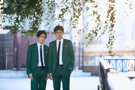 写真左から、多田智佑、桑原雅人。トレードマークは、おそろいの緑のスーツ