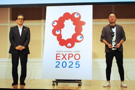 　２０２５年日本万博博覧会ロゴマーク最優秀作品発表記者会見に登壇した石毛博行事務総長（左）と最優秀作品に選ばれたチームイナリの代表シマダタモツさん（２０２０年８月２５日・大阪市）