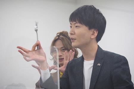 　開口一番、「ご挨拶代わりといってはなんですが…」と、フォークを使ったマジックを披露し、取材陣を圧倒した新子。後ろで主演俳優・池田も力添え？（２５日、大阪市内）