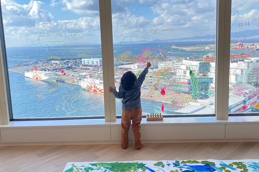 　大阪湾を望む最上階のガラス窓に自由に画を描く子ども