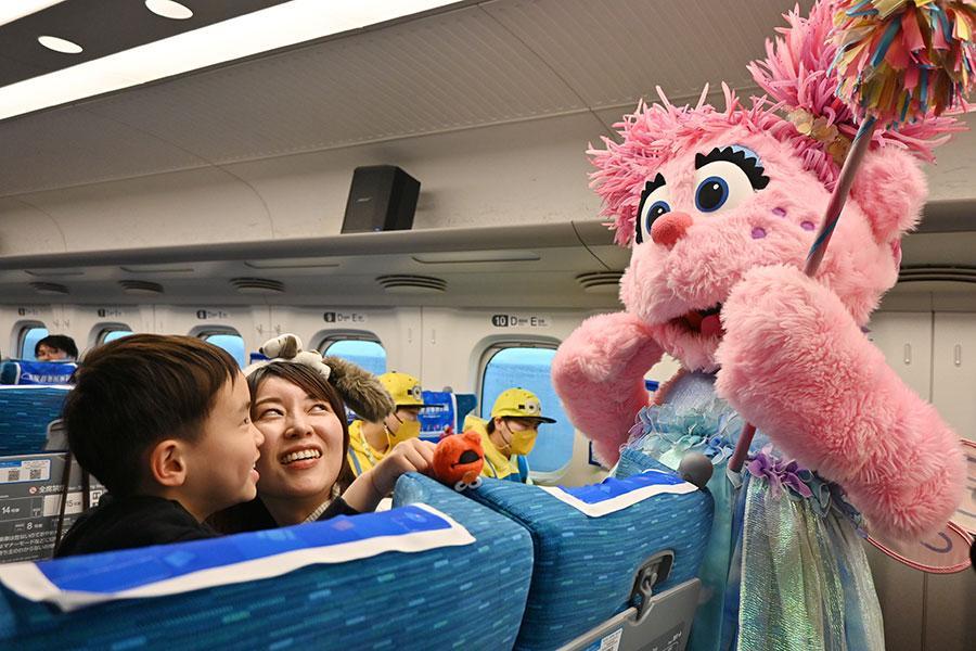 　新幹線の車内でアビーとコミュニケーションを取り、笑顔になる子ども（３月２６日）