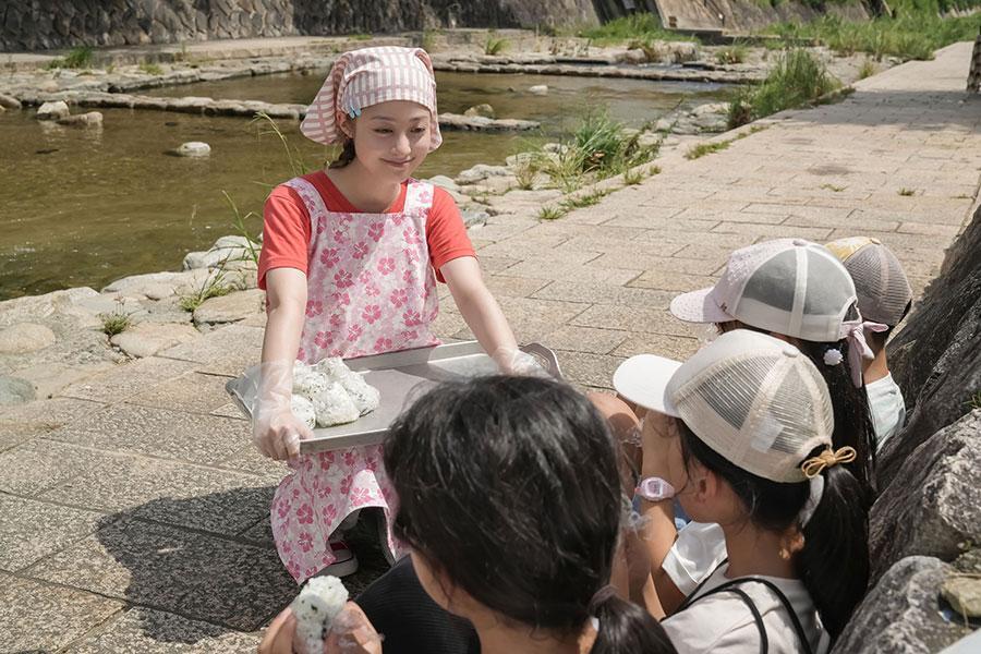 　『おむすび』第５０回より、子どもたちに炊き出しのおむすびを配る結（橋本環奈）　©ＮＨＫ