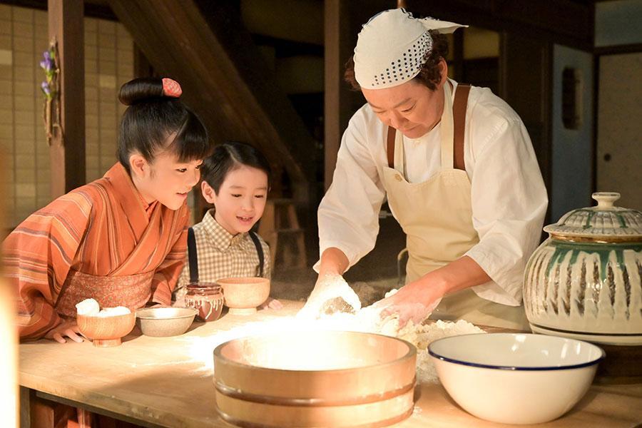 　『あんぱん』第８回より。あんぱんを作るパン職人・草吉と、その様子を見る２人。写真左から、のぶ（永瀬ゆずな）、嵩（木村優来）、草吉（阿部サダヲ）（Ｃ）ＮＨＫ