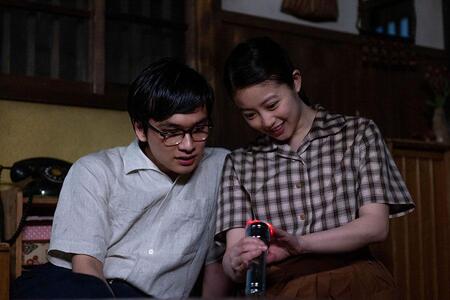 　『あんぱん』第１００回より。懐中電灯に手を当てるのぶ（今田美桜）と、その様子を見る嵩（北村匠海）©ＮＨＫ