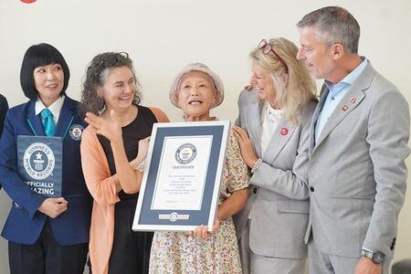 　「万博おばあちゃん」こと山田外美代さん、７６歳。万博で仲良くなったパビリオンスタッフがお祝いにかけつけた（中央・９月５日 Ｌｍａｇａ.ｊｐ撮影）