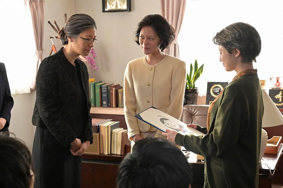 『あんぱん』第129回より。嵩が作ったキャラクターを、のぶの母校の教師・黒井雪子（写真左、瀧内公美）に贈呈するのぶ（写真右、今田美桜）（C）NHK