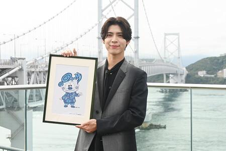 　「うずしおビジョン」の除幕式に登壇したｔｉｍｅｌｅｓｚ・松島聡。鳴門海峡をバックに自身が手がけたキャラクター「淡路うず助」の原画と撮影（１０月１６日・道の駅うずしお）
