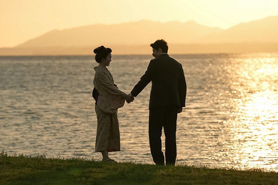 　『ばけばけ』第６５回より。手を繋いで宍道湖畔を散歩するトキ（高石あかり）とヘブン（トミー･バストウ）©ＮＨＫ