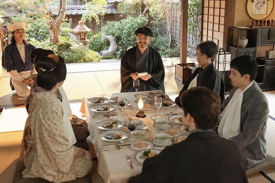 『ばけばけ』第76回より。パーティーの最中、ヘブンの家を訪れた新聞記者・梶谷（写真中央、岩崎う大）（C）NHK