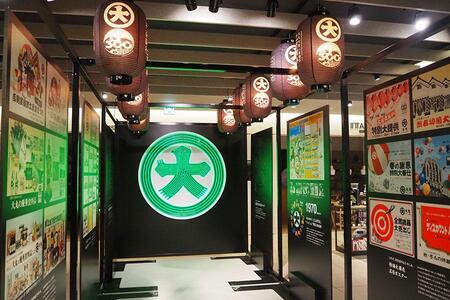 　屋上看板を模した「大」マーク看板のフォトスポット。周りにはポスターなどの展示も