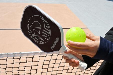 　「ピックルボール」のパドルとボール。テニスよりもちょっとネットの高さは低め