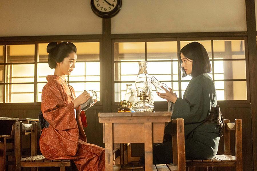 　『風、薫る』第２２回より。ガラスを拭きながら話すりん（写真左、見上愛）と直美（写真右、上坂樹里）　©ＮＨＫ