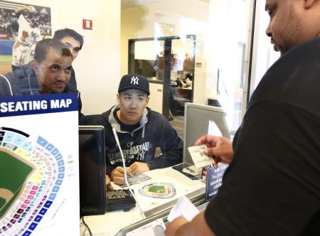 　チームの帽子をかぶって窓口に座り、試合のチケットを販売するヤンキース・田中将＝ニューヨーク（共同）