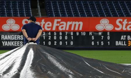 　ヤンキース-レンジャーズ戦が雨で中断し、球場にシートを掛けるグラウンドキーパー＝ニューヨーク（ＡＰ＝共同）
