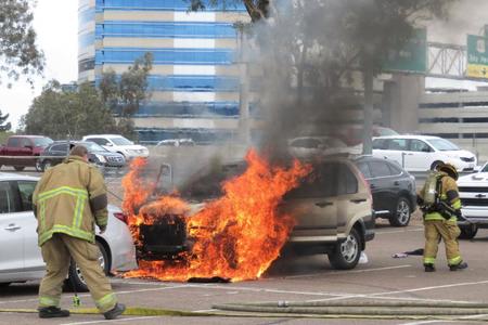 　駐車場で炎上した車を消火する消防員たち（撮影・小林信行）