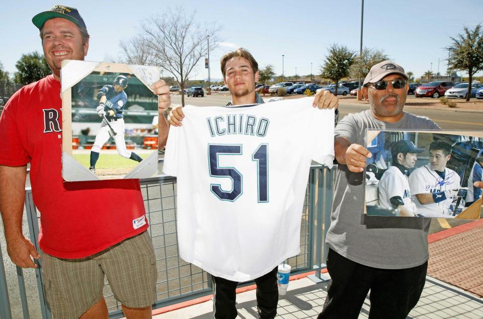 　球団施設の近くで、ユニホームや写真を手にイチローの到着を待ちわびるファン（共同）