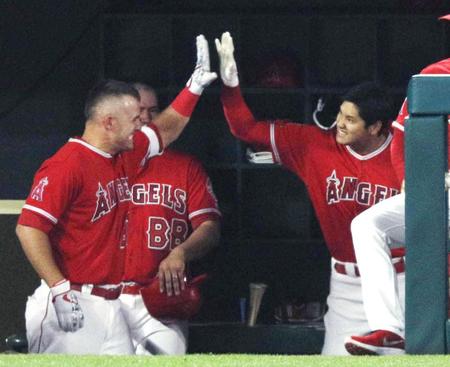 　アスレチックス戦の２回、３試合連続となる本塁打を放ち、ベンチでトラウト（左）とタッチ交わすエンゼルス・大谷＝アナハイム（共同）