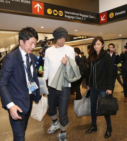 　２２日、米シアトルの空港に到着したイチロー元選手（中央）。右は弓子夫人（共同）
