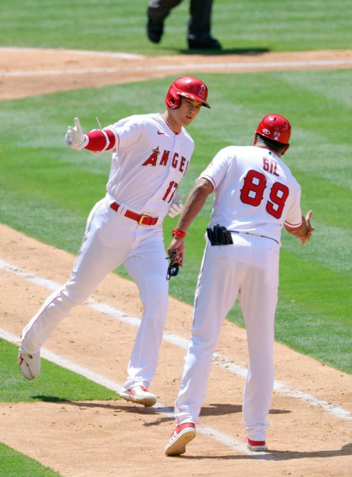 ブルージェイズ戦の３回、２打席連続となる11号２ランを放ち一塁コーチとタッチを交わすエンゼルス・大谷＝アナハイム（共同）