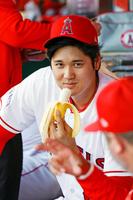 　試合前、ベンチでバナナを片手に話す大谷（共同）