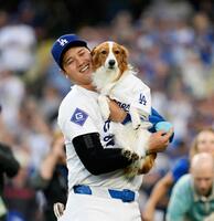 　“始球式”を行い、ドジャース・大谷に抱えられる愛犬のデコピン（共同）