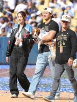 　優勝報告会を終え、愛犬デコピンを抱いて引き揚げる米大リーグ、ドジャースの大谷翔平。左は妻真美子さん＝１１月１日撮影（共同）