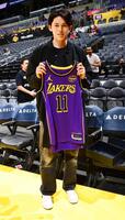 　訪問したレーカーズのユニホームを手にポーズをとるドジャース移籍が決まった佐々木（ＮＢＡＥ・ゲッティ＝共同）