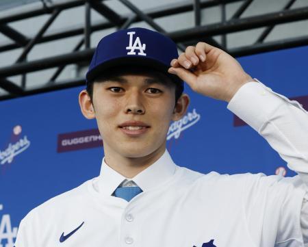 　米大リーグ、ドジャースの入団記者会見で、背番号１１のユニホームに袖を通し撮影に応じる佐々木朗希投手＝２２日、ロサンゼルス（共同）