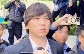 水原一平被告　開廷４０分前に法廷へ　黒のスーツ姿　後ろ髪はスーツの襟にかかるほど