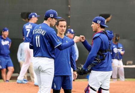 　ブルペンで投球練習後、捕手とタッチを交わす佐々木