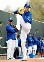 　ブルペンで投球練習する佐々木。左はロバーツ監督