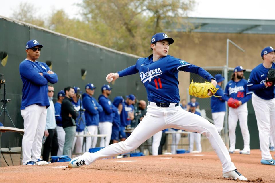 　ブルペンで投球練習する佐々木。左端はロバーツ監督