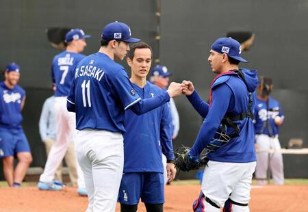 　投球練習後、捕手バーンズとタッチを交わす佐々木（共同）