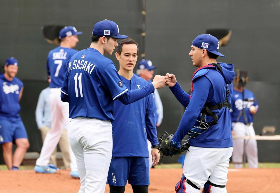 　投球練習後、捕手バーンズとタッチを交わす佐々木（共同）