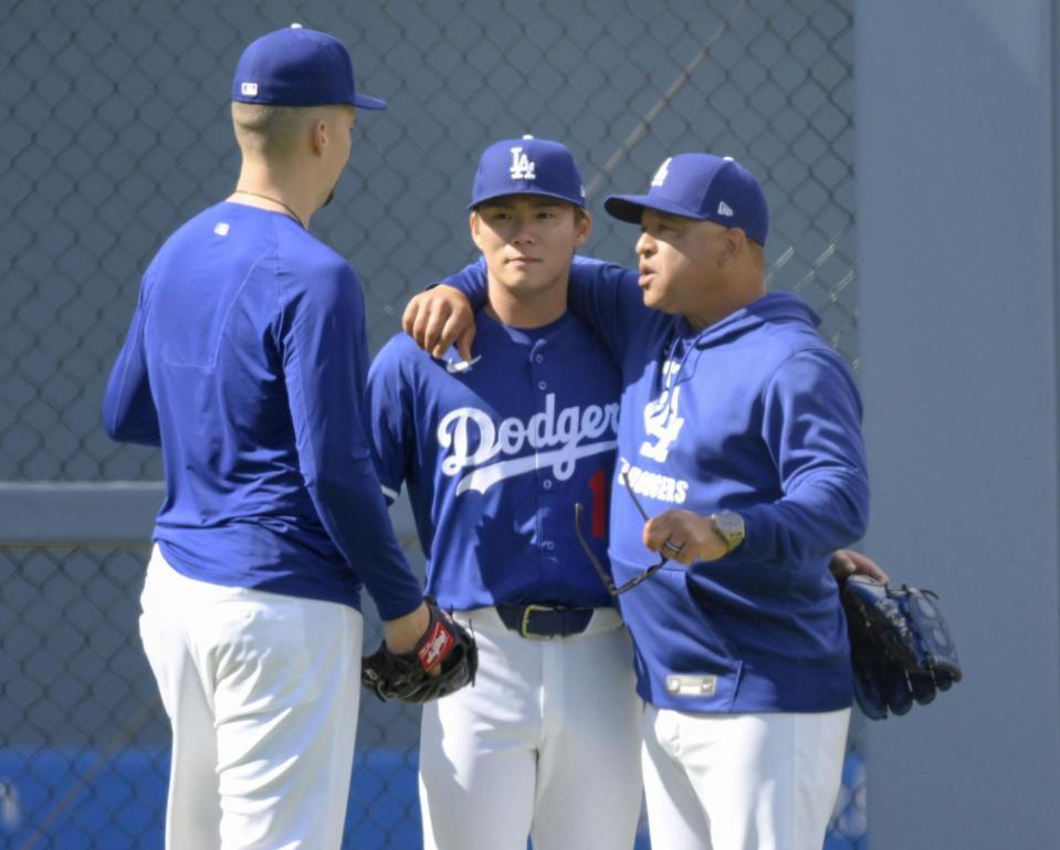 　ブルペンでの投球練習を終え、ロバーツ監督（右）らと話す山本（中央）＝共同