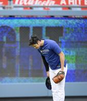 　キャッチボールの“暴投”でボールが客席に飛び込み、脱帽して頭を下げる大谷（共同）