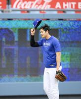 　キャッチボールの“暴投”でボールが客席に飛び込み、脱帽して頭を下げる大谷（共同）