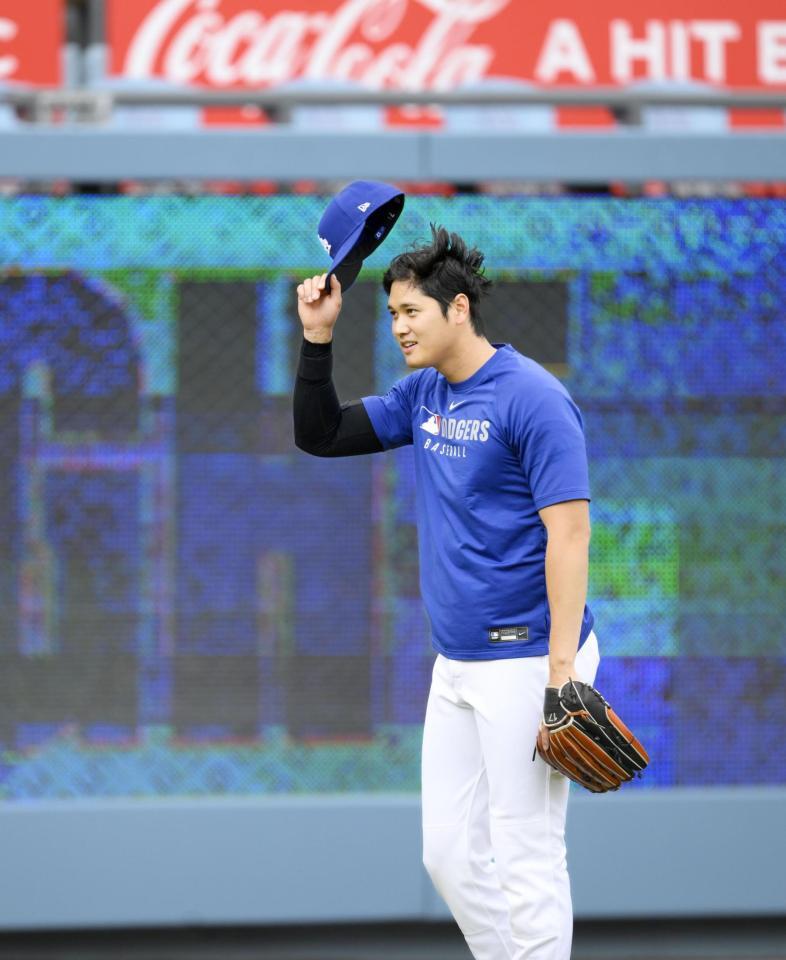 　キャッチボールの“暴投”でボールが客席に飛び込み、脱帽して頭を下げる大谷（共同）