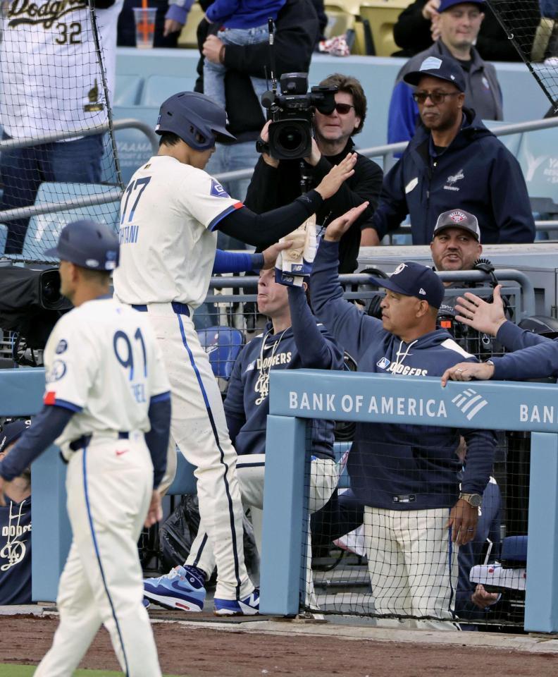 　１回、後続の二塁打で生還し、ロバーツ監督（右）に迎えられる大谷（共同）