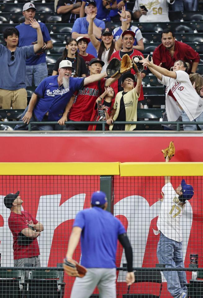 　ドジャース・大谷（手前）が投げ入れたボールを捕ろうとする観客（共同）