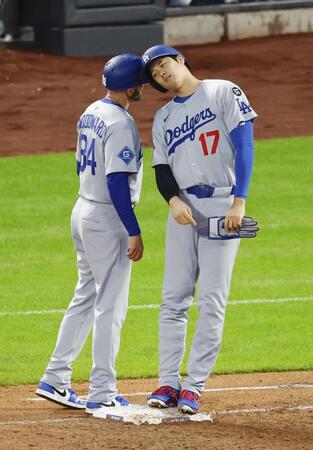 　３回、四球で出塁し、一塁コーチとヘルメットを合わせる大谷（右）＝共同