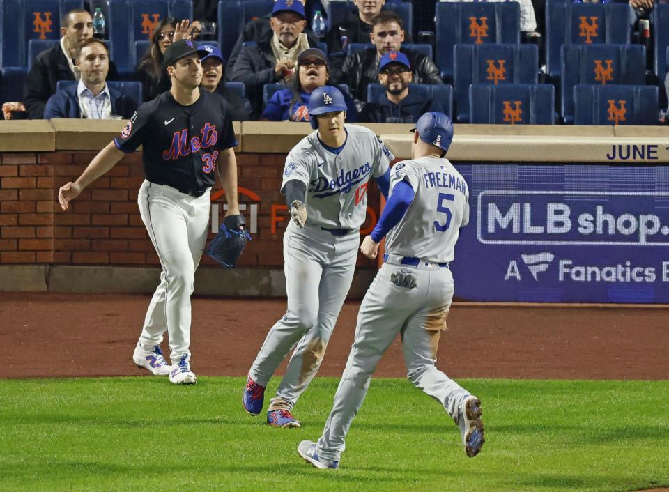 　３回、後続の２点打で生還し、フリーマン（５）とタッチを交わす大谷（共同）