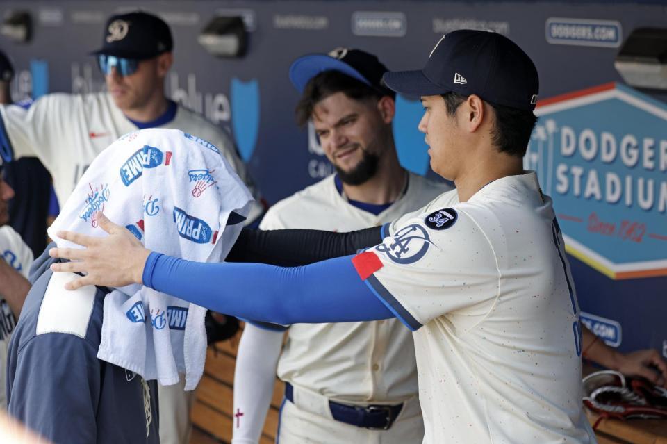 　試合前のベンチで佐々木（左）にタオルをかぶせる大谷（共同）